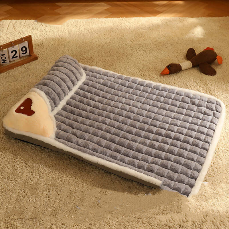 Cozy gray pet bed with plush fabric on a carpeted floor, featuring a toy duck and a table calendar displaying November 29.